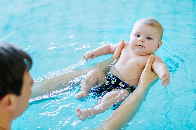 A baby is floating in the water with his mother.