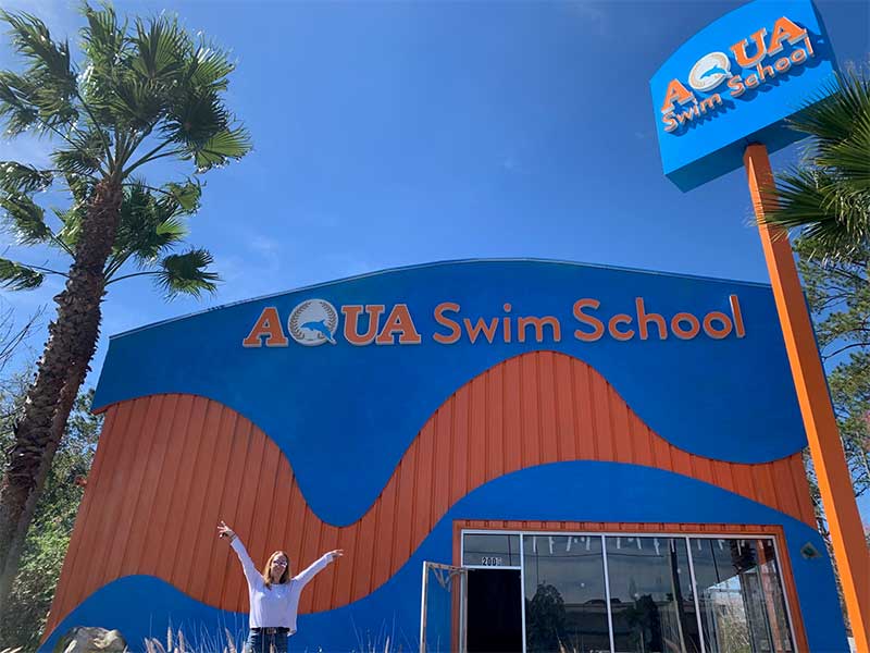 A person standing in front of an aqua swim school building.