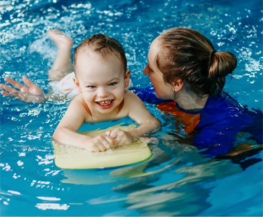 A woman and baby in the water with a float.