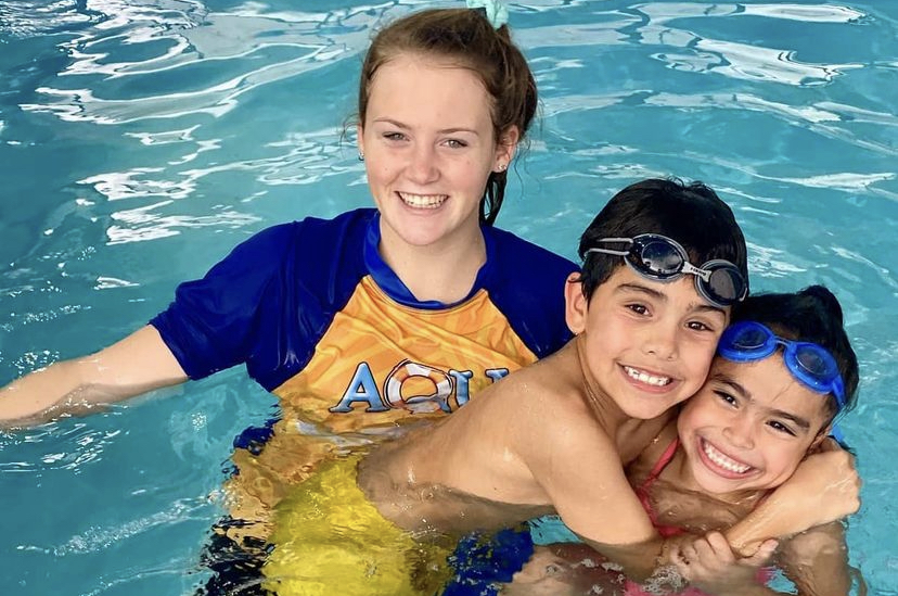 Three children are swimming in a pool.