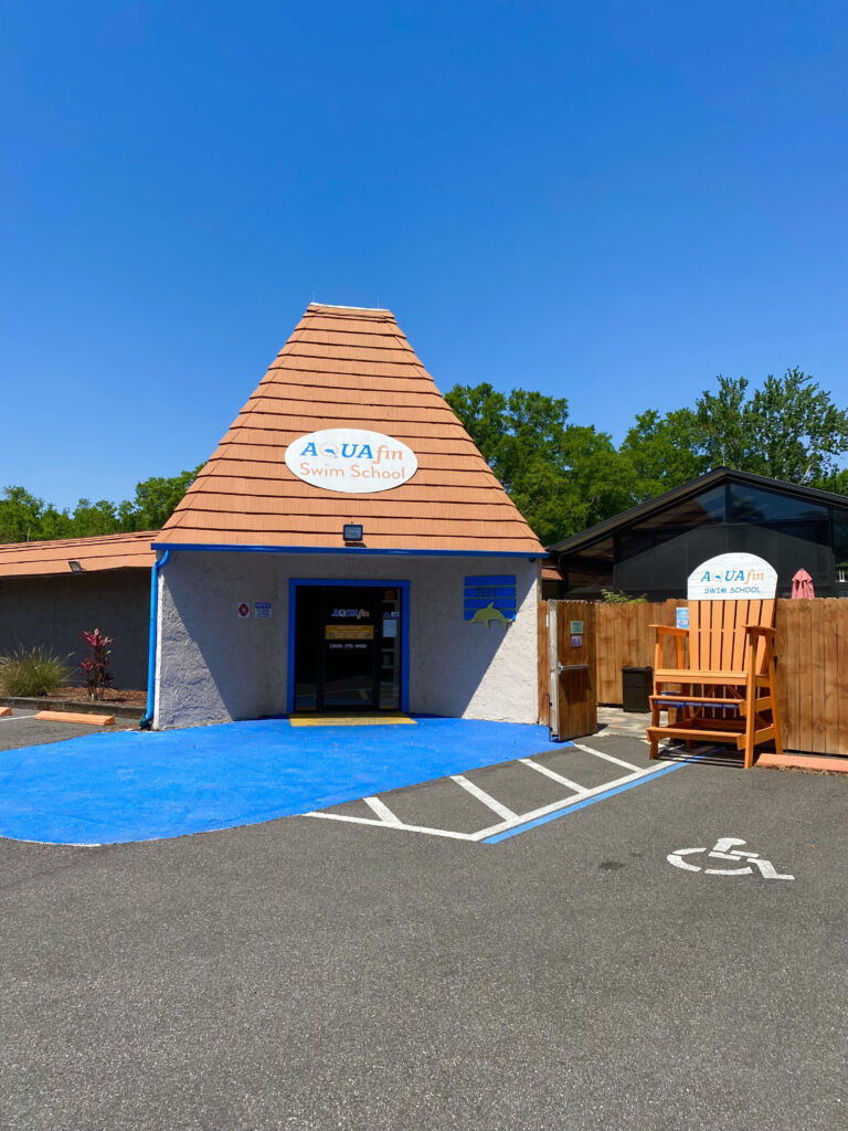 A blue and white building with a wooden bench in front of it.
