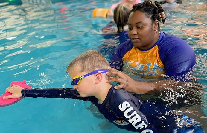 A woman helping a boy in the water